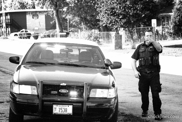 HARVEY IL - AUGUST 20, 2014: "Hey you, come here!" Officer Wright of the Dixmoor Police Department singles out a journalist for eviction from the area during a hostage standoff in Harvey, IL on August 20, 2014