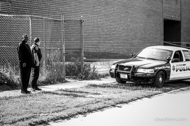 HARVEY IL - AUGUST 20, 2014: Bob Jackson, Executive Director of Roseland CeaseFire, stands looking bewildered as to why the police forced a journalist leave the area during a hostage standoff in Harvey, IL on August 20, 2014.