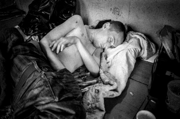 CHICAGO, ILLINOIS - SEPTEMBER 1, 2014 - John Lee, recovering from a blood infection which caused by a broken needle that was in his foot, sleeps on Hepatitis Boulevard.