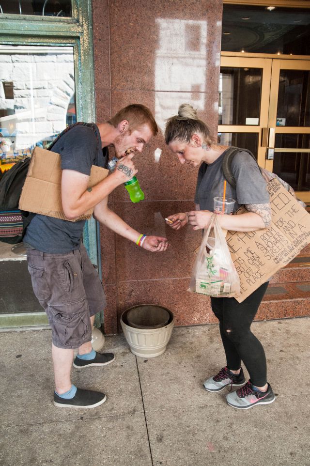 CHICAGO, IL. Sep 6, 2015 - Heroin addicts, Caleb Higgins, age 26 (left), and Mandrell White, age 34 (right), dig through a public cigarette receptacle searching for any butts that might be worth smoking. In Chicago, a bag of heroin is cheaper than a pack of cigarettes.