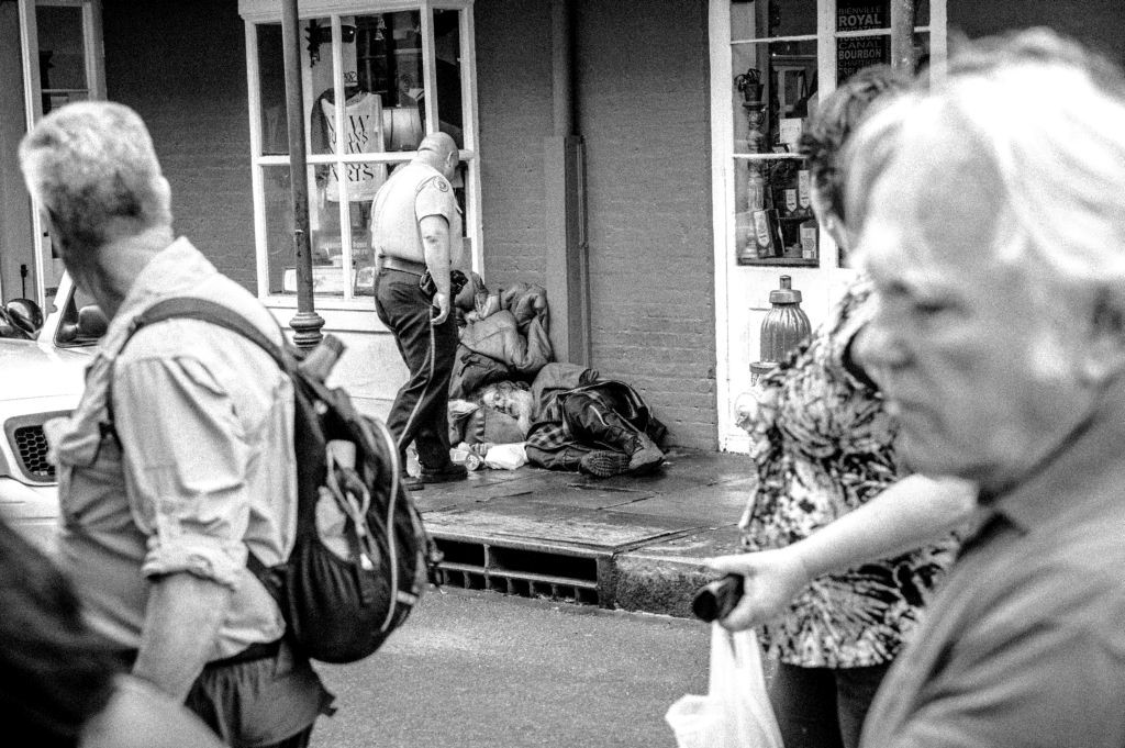 A New Orleans police officer attempts to wake up a homeless man sleeping on the sidewalk in the French Quarter two days before Christmas, 2015. 